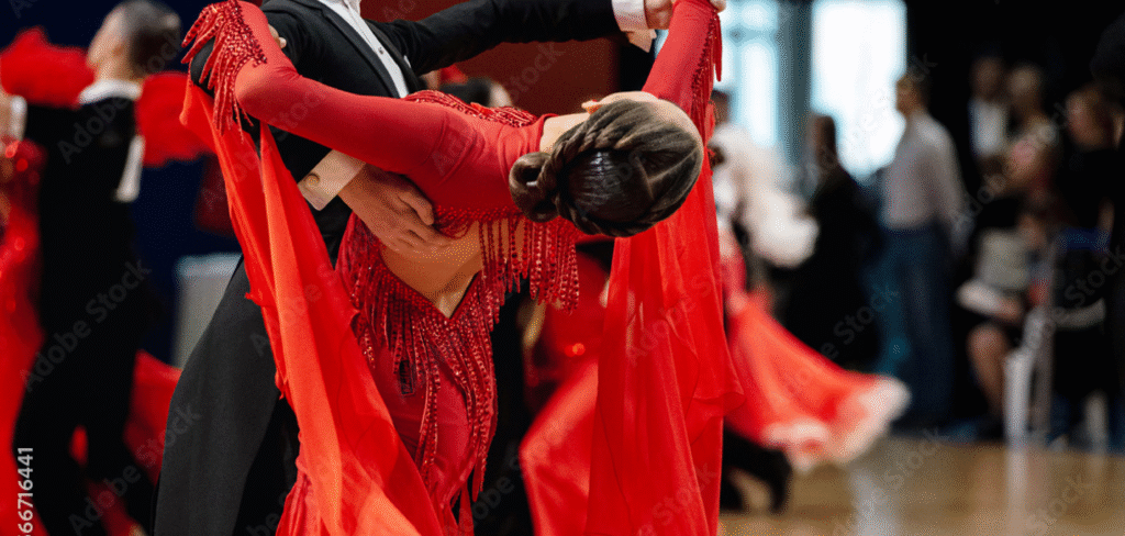 Ballroom dancers performing a dramatic pose; woman in red sequin dress and man in black suit during a competitive dance event