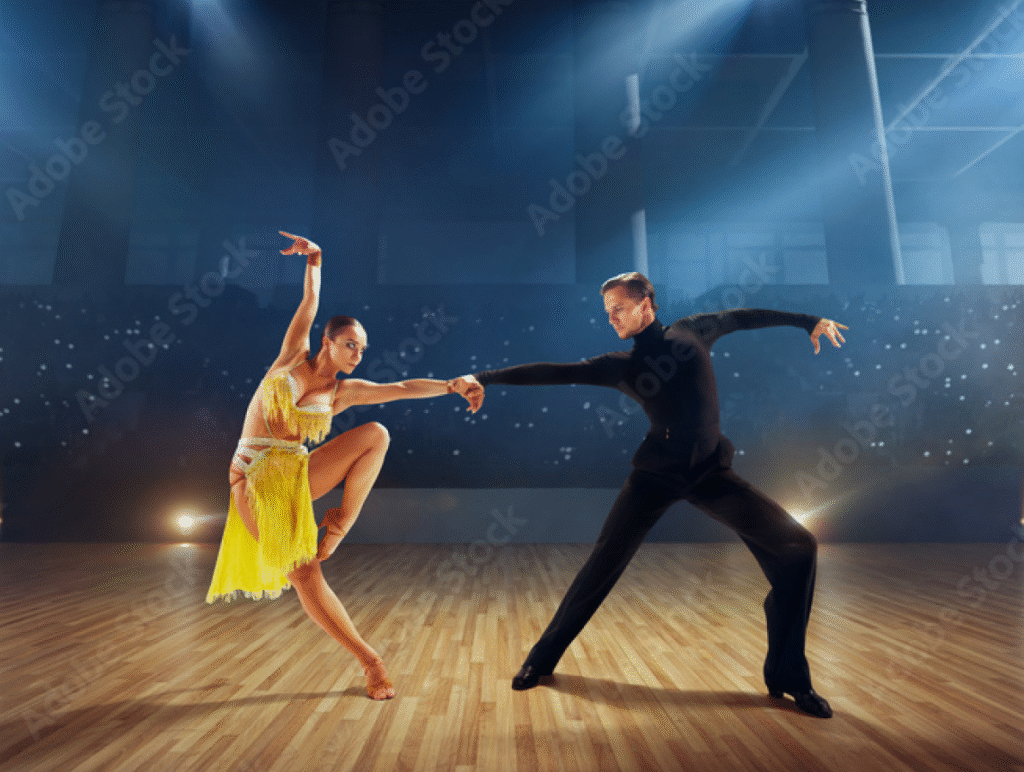 Two ballroom dancers performing on a polished wooden stage—female in a yellow fringe dress, male in sleek black attire—striking expressive poses under theatrical lighting.